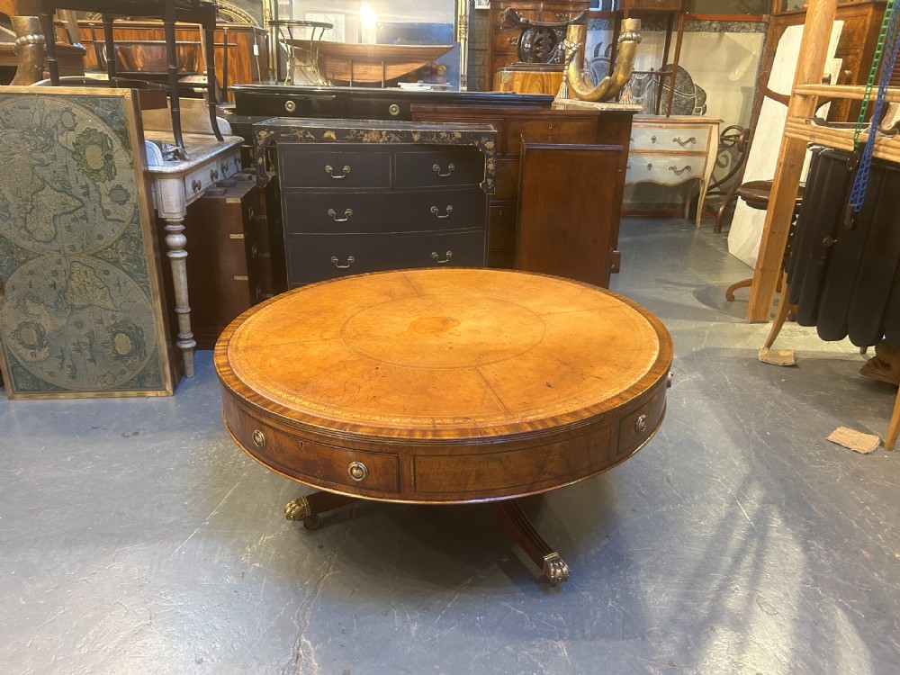A low circular mahogany drum table featuring a gold-tooled leather top, frieze drawers with brass pulls, and a pedestal base with brass lion paw castors. View VIII