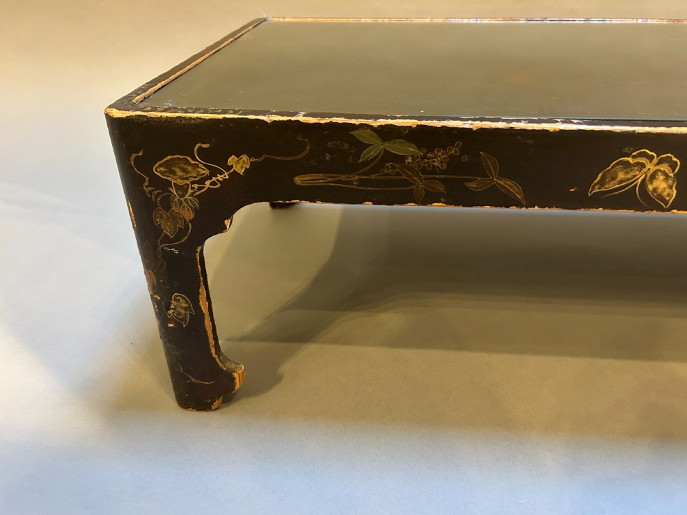 A low rectangular antique Chinese black lacquered coffee table decorated with hand-painted floral motifs and corner apron detail. View IV