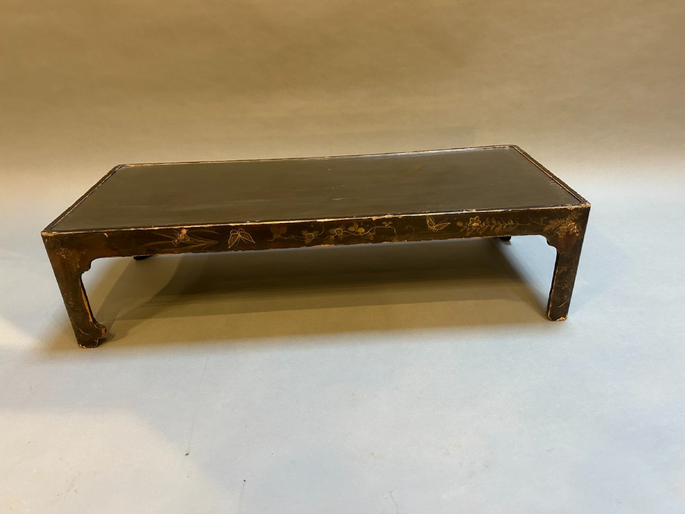A low rectangular antique Chinese black lacquered coffee table decorated with hand-painted floral motifs and corner apron detail. View V