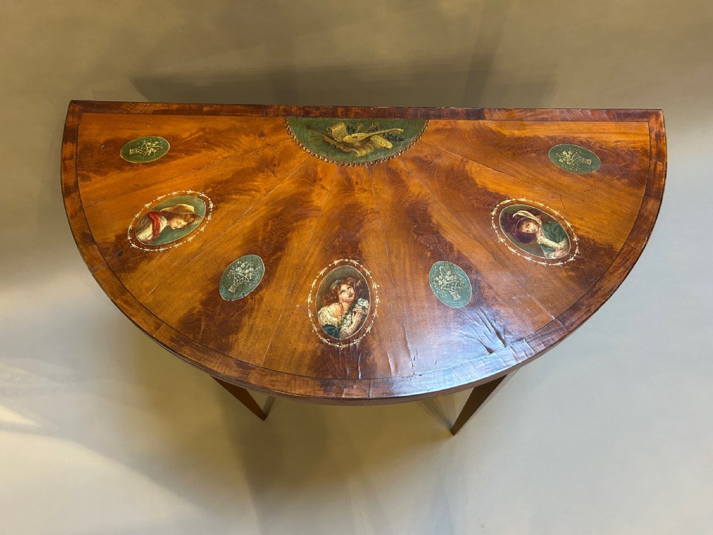 A 19th-century Sheraton style demilune card table featuring painted portrait ovals, fan marquetry, and tapered legs. View II