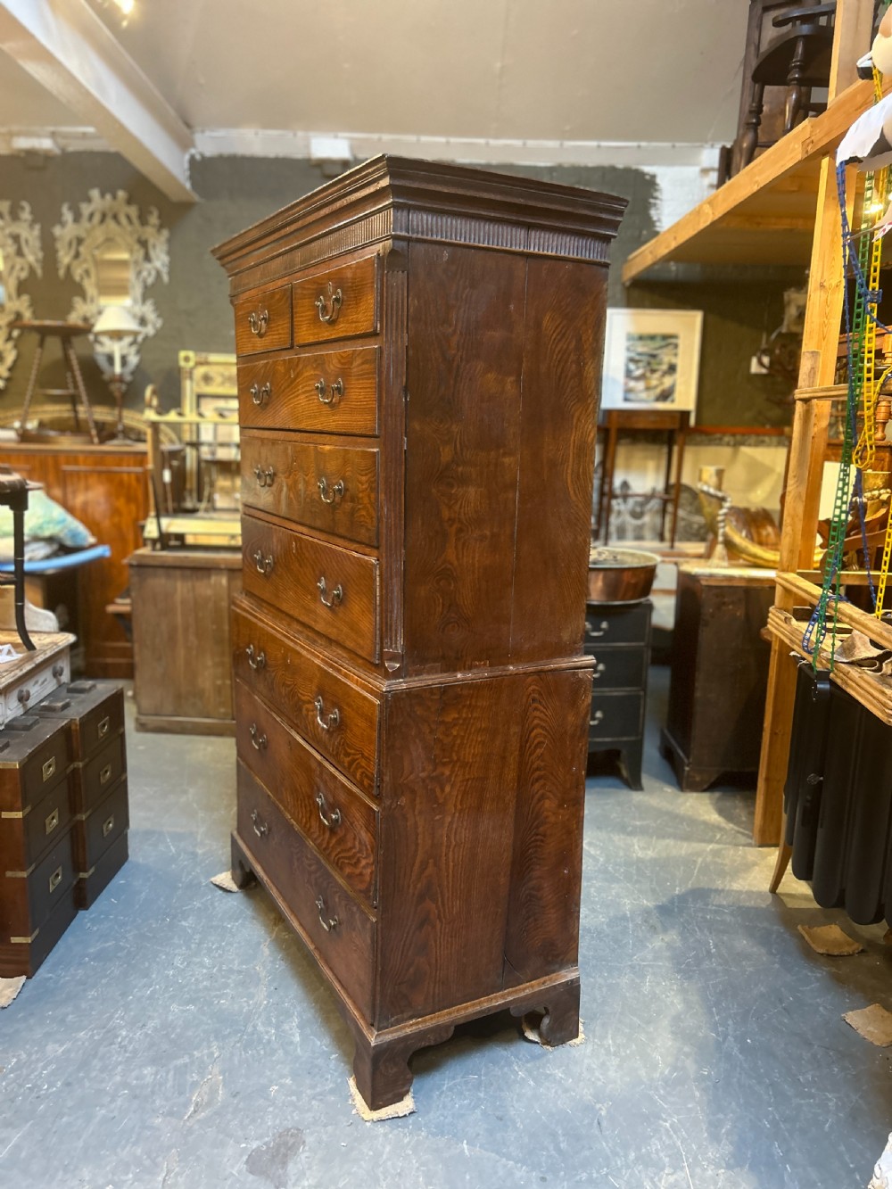 A tall George III oak chest-on-chest featuring two short over three long drawers on the upper section, three long drawers on the lower section, brass swan-neck handles, and bracket feet. View IV