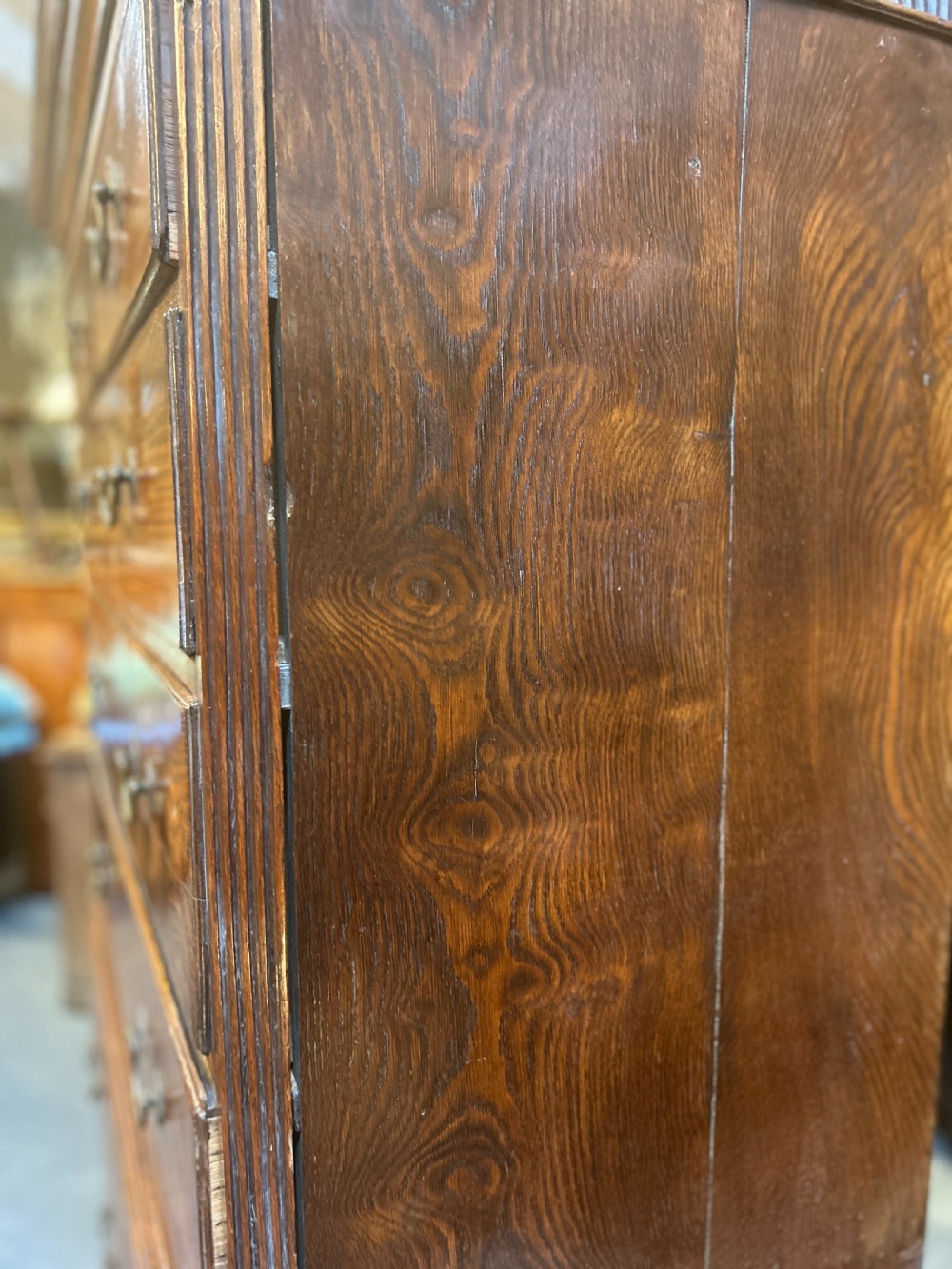 A tall George III oak chest-on-chest featuring two short over three long drawers on the upper section, three long drawers on the lower section, brass swan-neck handles, and bracket feet. View V