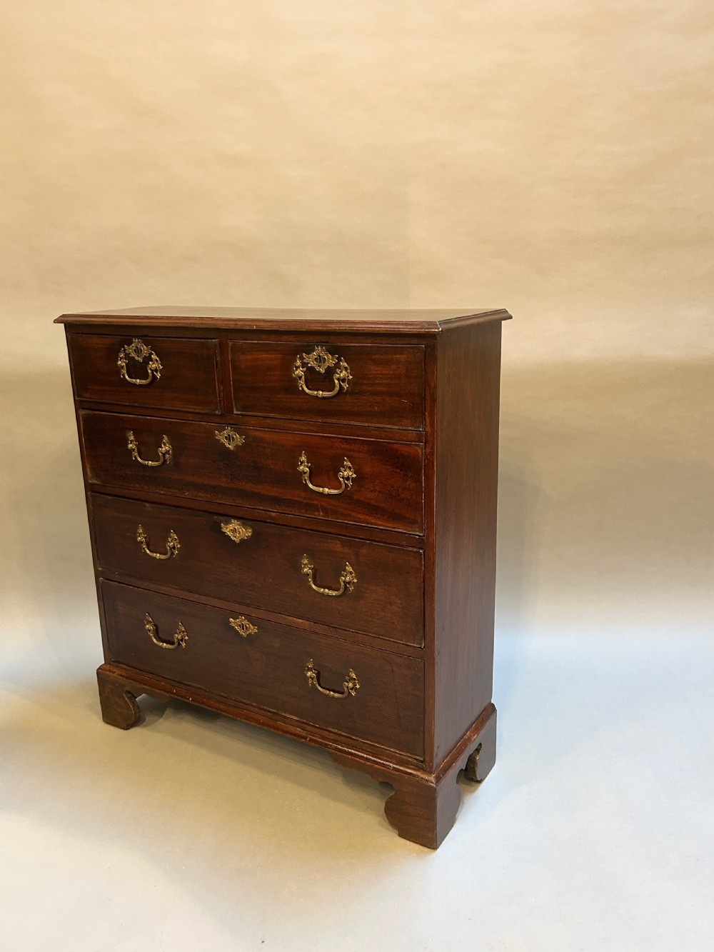 A George III dark mahogany hall chest of drawers featuring brass swan-neck handles, keyhole escutcheons, and bracket feet.