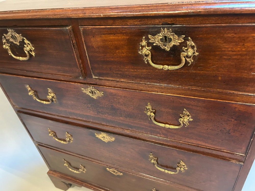 A George III dark mahogany hall chest of drawers featuring brass swan-neck handles, keyhole escutcheons, and bracket feet. View III