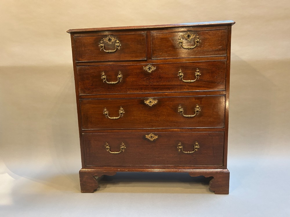 A George III dark mahogany hall chest of drawers featuring brass swan-neck handles, keyhole escutcheons, and bracket feet. View IV