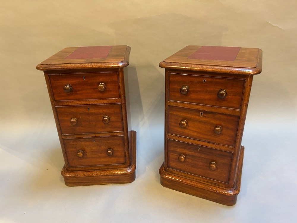 A pair of matching Victorian mahogany bedside chests of drawers featuring inset red leather tops and three drawers with turned wooden knobs. View II