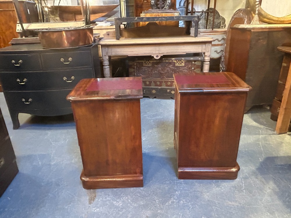A pair of matching Victorian mahogany bedside chests of drawers featuring inset red leather tops and three drawers with turned wooden knobs. View X