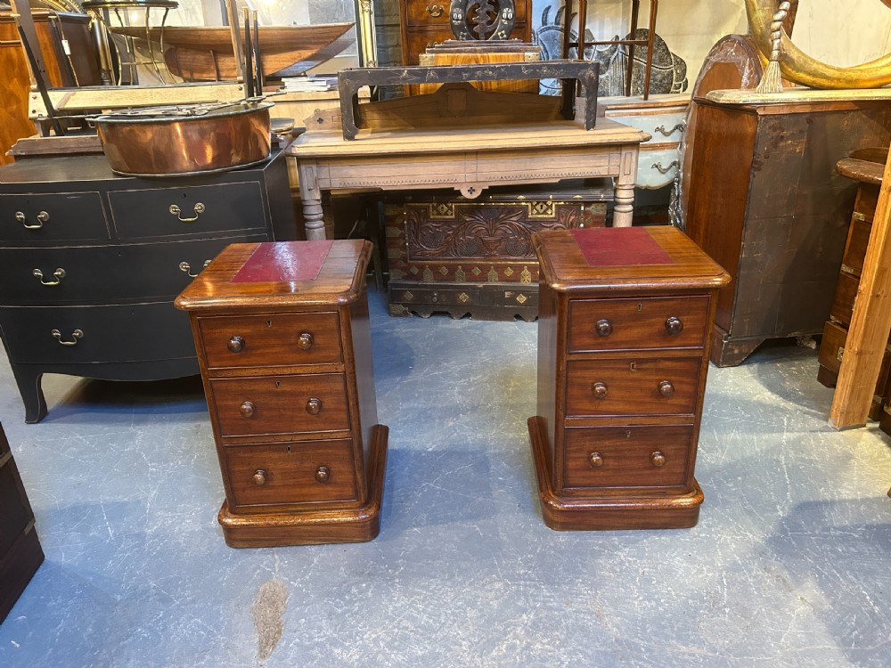 A pair of matching Victorian mahogany bedside chests of drawers featuring inset red leather tops and three drawers with turned wooden knobs. View XIII