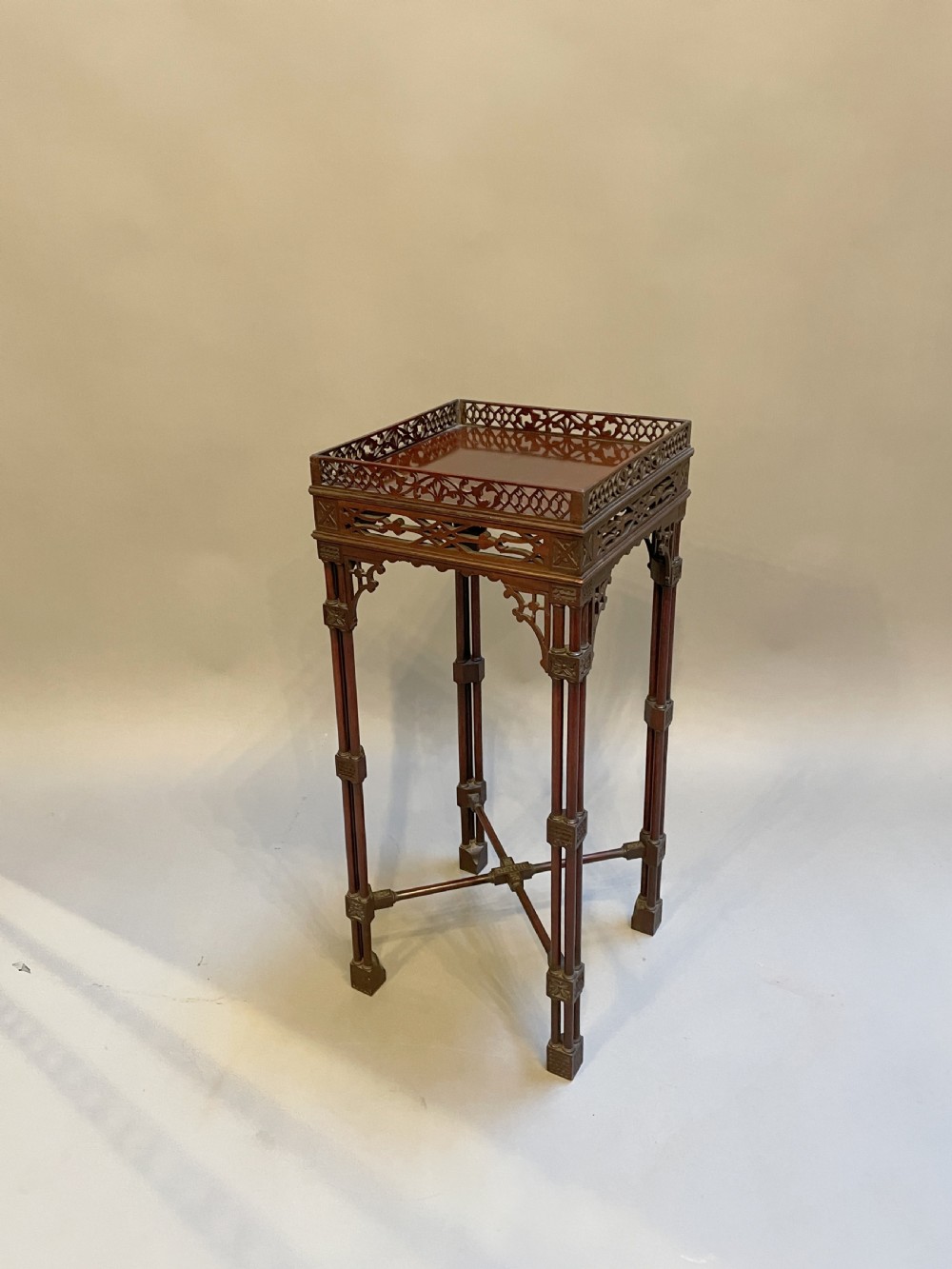 A tall mahogany Chippendale revival lamp table featuring a pierced fretwork gallery top, clustered column legs, and an X-form stretcher.