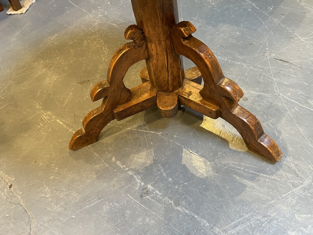 An 18th-century rustic pine pedestal table featuring a round plank top and carved tripod legs with a warm timber patina. View IV