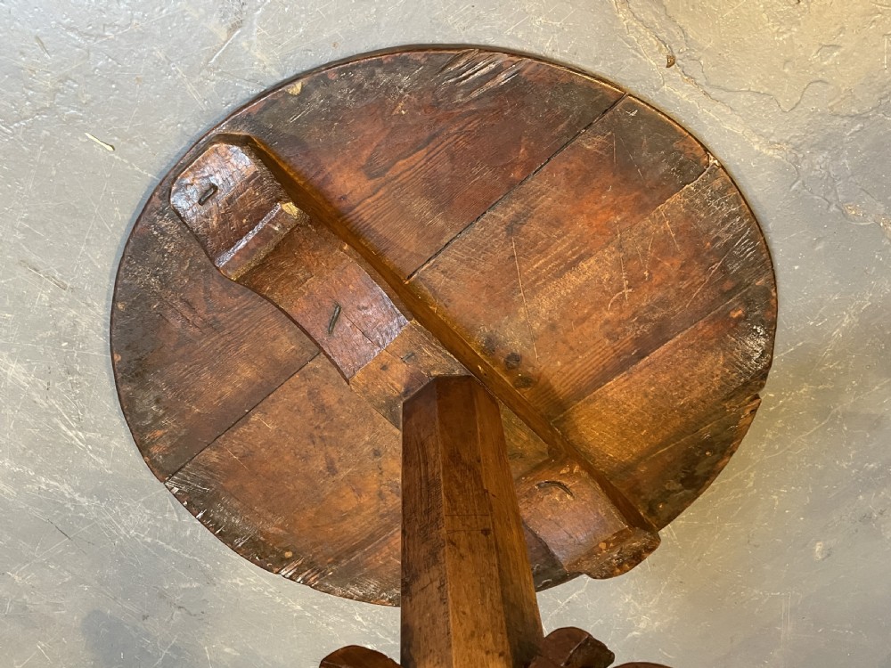 An 18th-century rustic pine pedestal table featuring a round plank top and carved tripod legs with a warm timber patina. View V