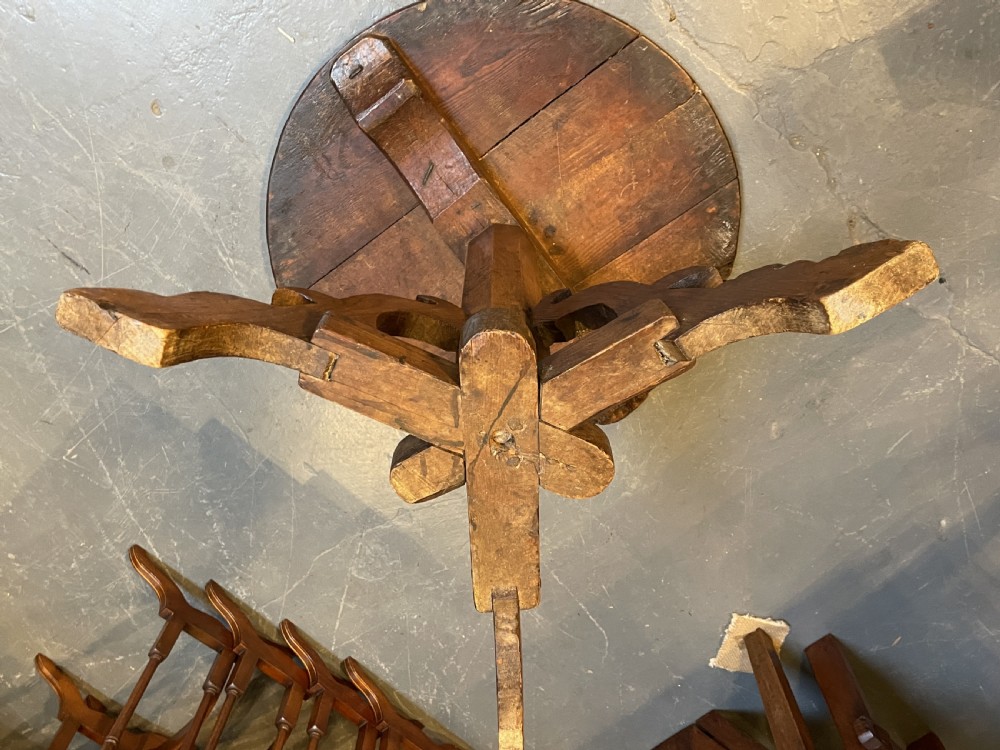 An 18th-century rustic pine pedestal table featuring a round plank top and carved tripod legs with a warm timber patina. View VI