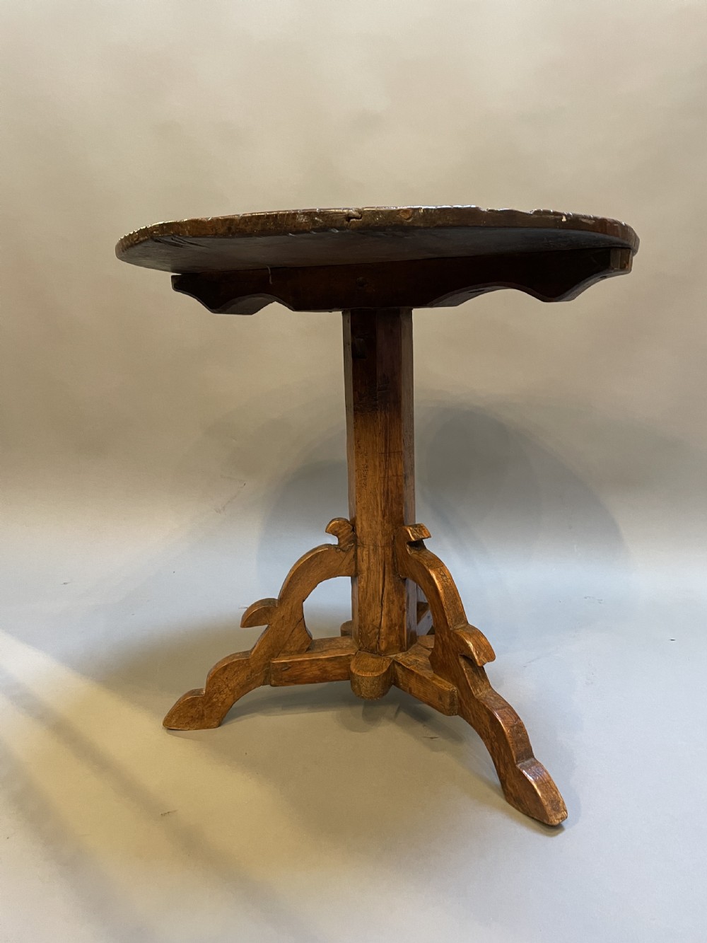 An 18th-century rustic pine pedestal table featuring a round plank top and carved tripod legs with a warm timber patina. View XII