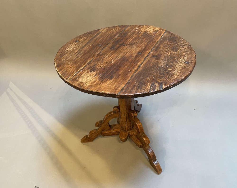 An 18th-century rustic pine pedestal table featuring a round plank top and carved tripod legs with a warm timber patina. View XIII