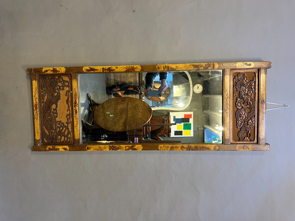 A tall, narrow timber wall mirror decorated with relief carvings of dragons and waves at the top and bottom, framed by gilt painted chinoiserie side borders. View II