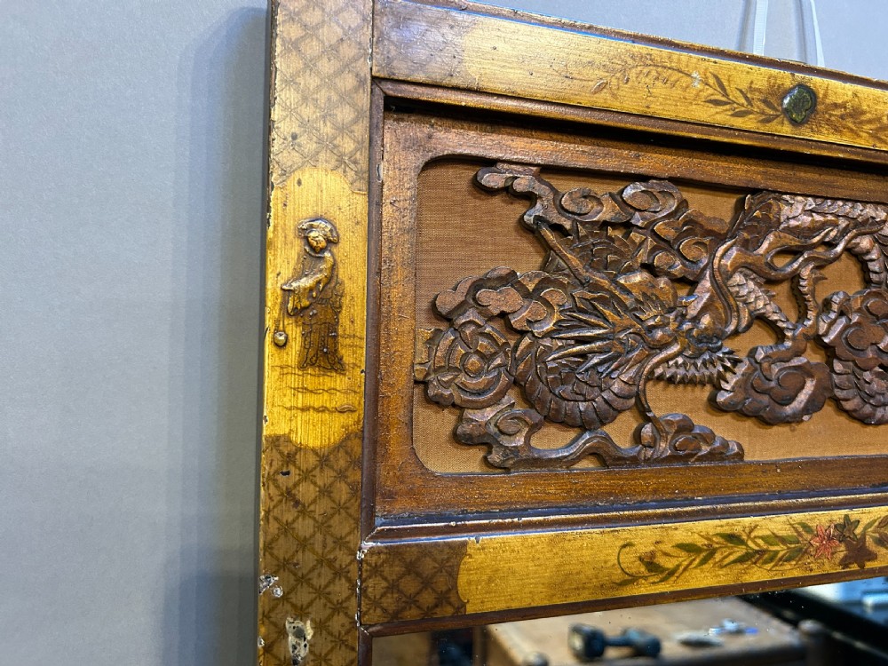 A tall, narrow timber wall mirror decorated with relief carvings of dragons and waves at the top and bottom, framed by gilt painted chinoiserie side borders. View III
