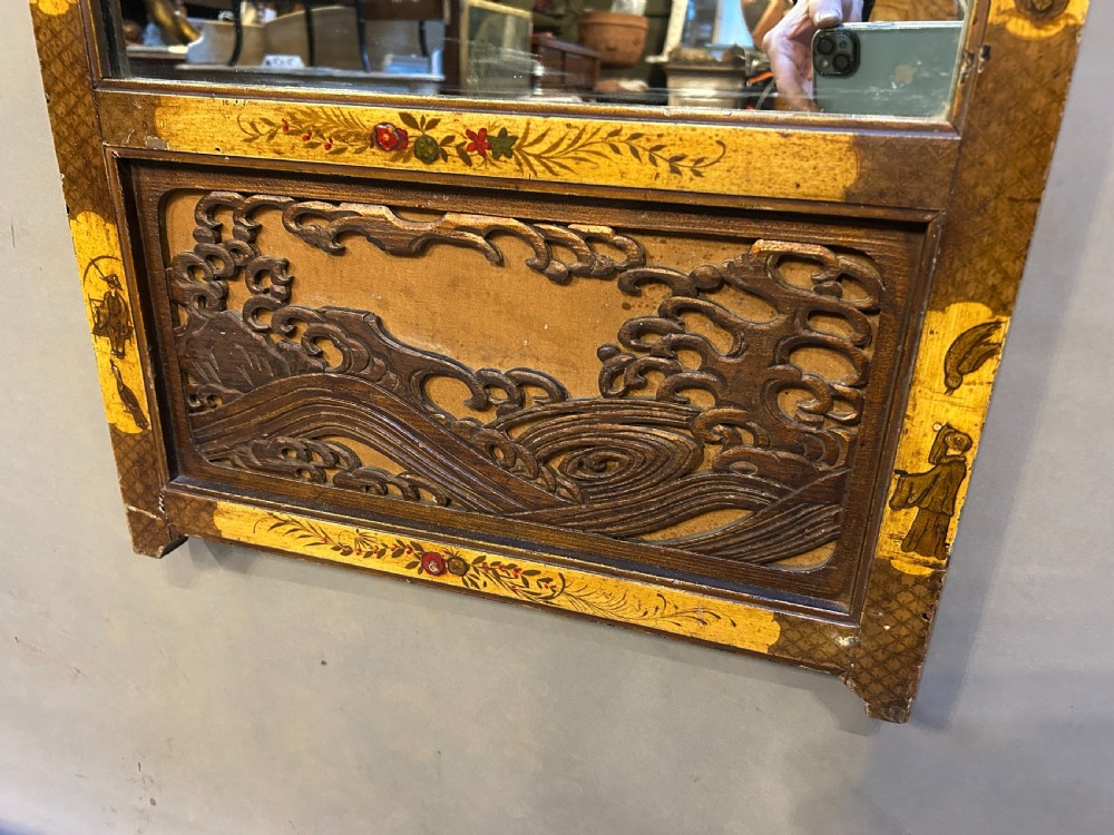 A tall, narrow timber wall mirror decorated with relief carvings of dragons and waves at the top and bottom, framed by gilt painted chinoiserie side borders. View V