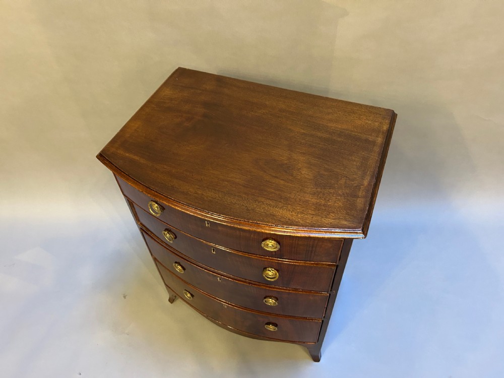 An Edwardian mahogany bow-front chest of drawers with four graduated drawers, circular brass handles, and splayed bracket feet. View II