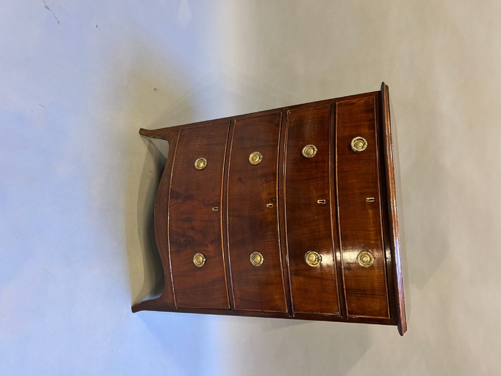 An Edwardian mahogany bow-front chest of drawers with four graduated drawers, circular brass handles, and splayed bracket feet. View III