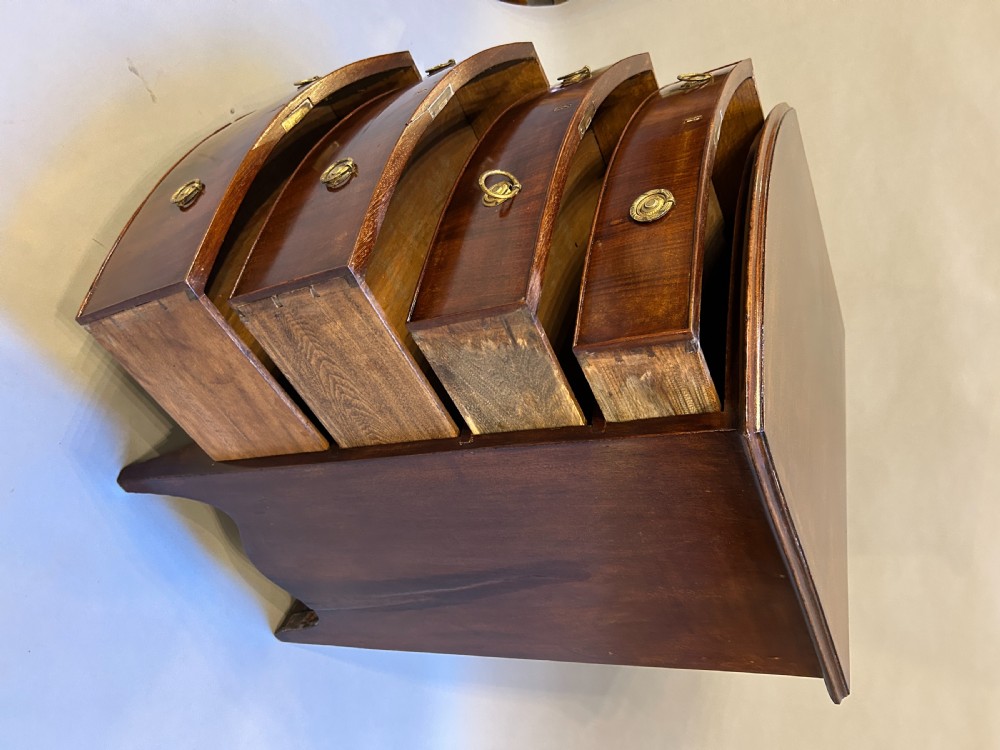 An Edwardian mahogany bow-front chest of drawers with four graduated drawers, circular brass handles, and splayed bracket feet. View V