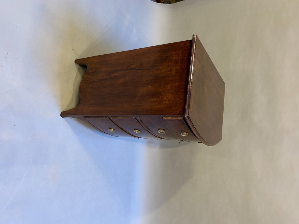 An Edwardian mahogany bow-front chest of drawers with four graduated drawers, circular brass handles, and splayed bracket feet. View VII