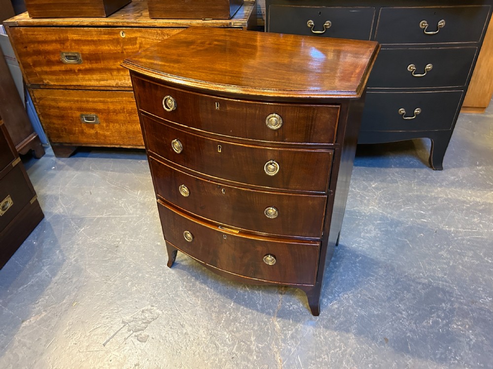 An Edwardian mahogany bow-front chest of drawers with four graduated drawers, circular brass handles, and splayed bracket feet. View VIII