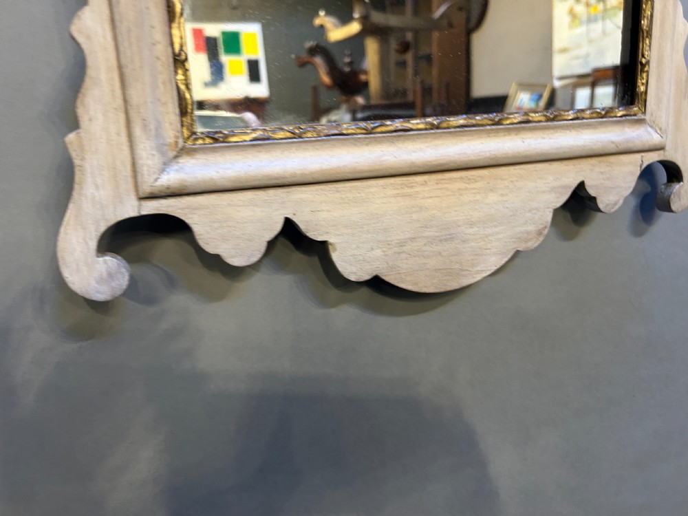 A fret-cut wall mirror featuring a pale bleached wood frame with a scrolled cresting silhouette, central carved patera motif, and a gilded inner rim holding rectangular glass. View III