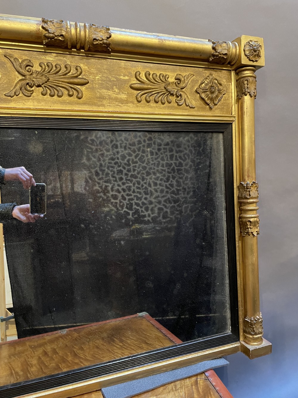 A large horizontal Regency gilt overmantel mirror featuring neoclassical side columns, a frieze with carved palmettes and rosettes, and an ebonised inner slip. View XI