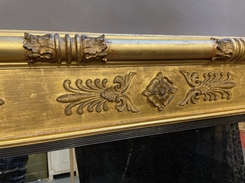 A large horizontal Regency gilt overmantel mirror featuring neoclassical side columns, a frieze with carved palmettes and rosettes, and an ebonised inner slip. View XIII