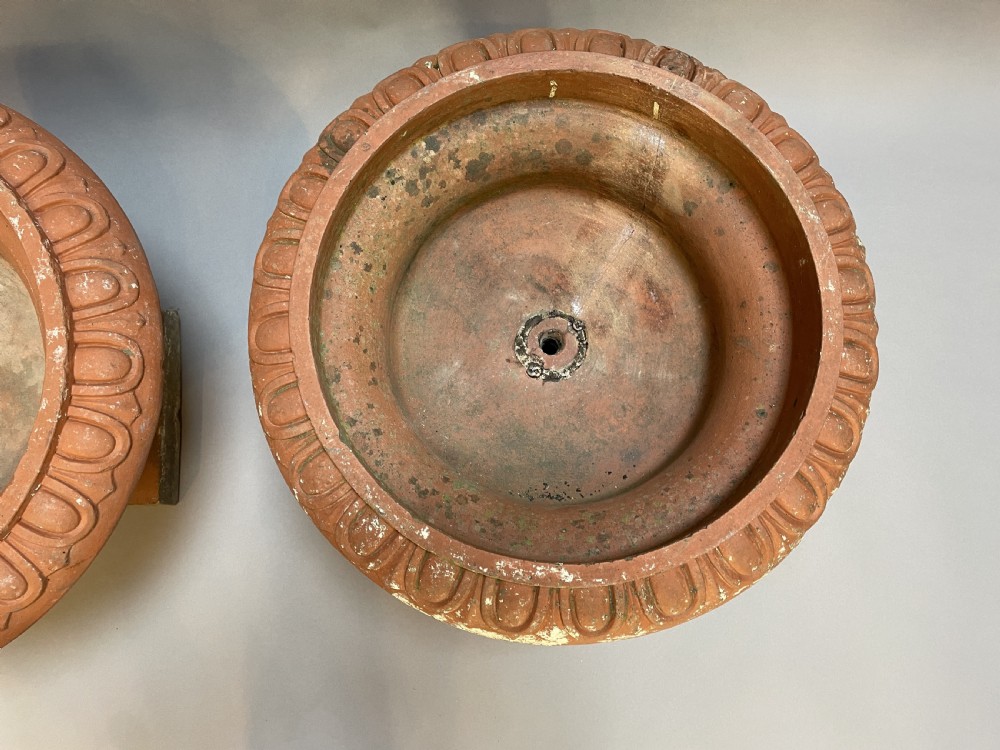 A pair of weathered terracotta Campana garden urns featuring wide egg-and-dart rims, gadrooned lower bowls, fluted stems, and square bases. View IV