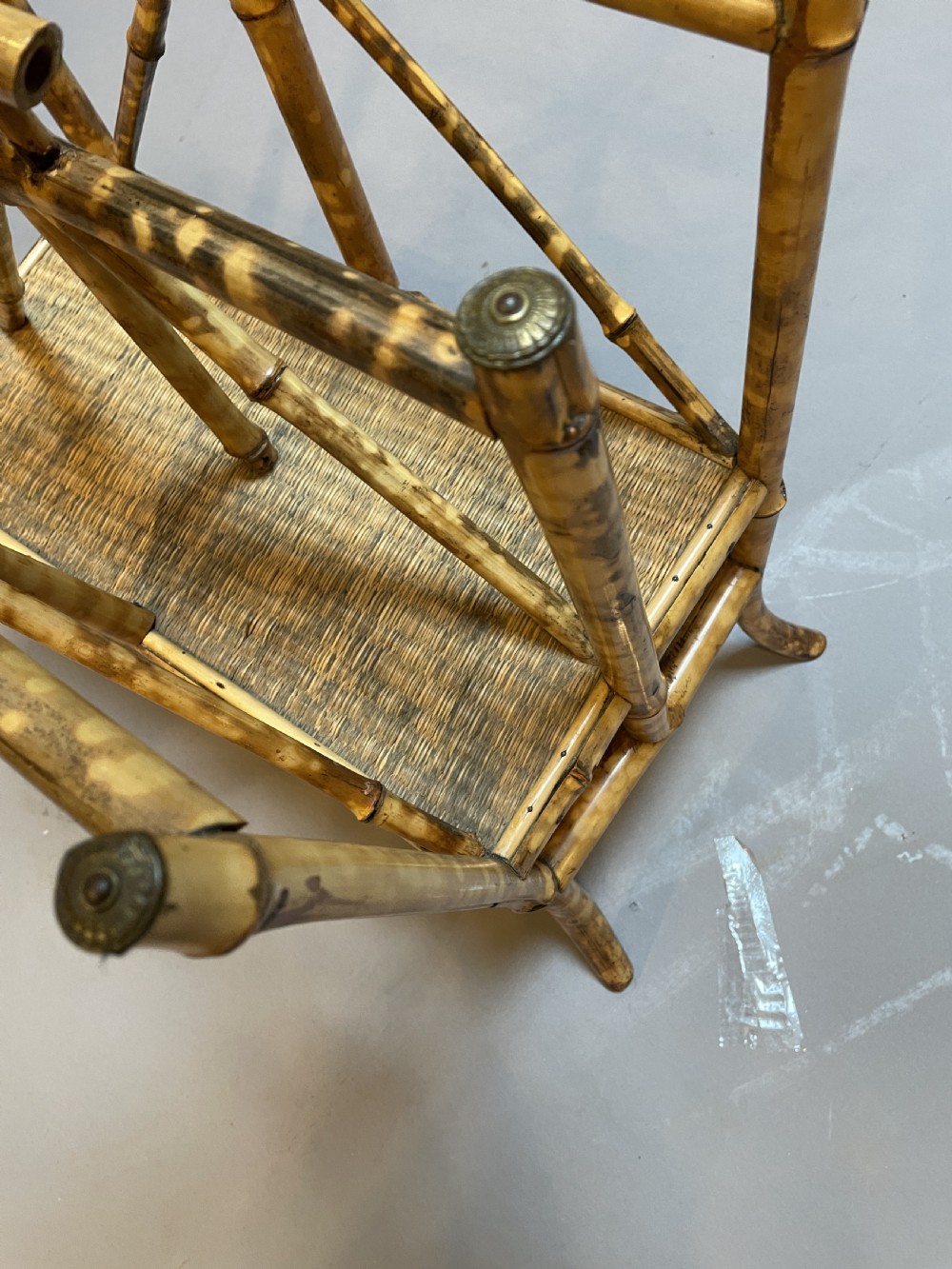 A late 19th-century bamboo canterbury rack featuring diagonal cross-bracing, a woven lower shelf, four partitioned sections, and metal capped finials. View IV
