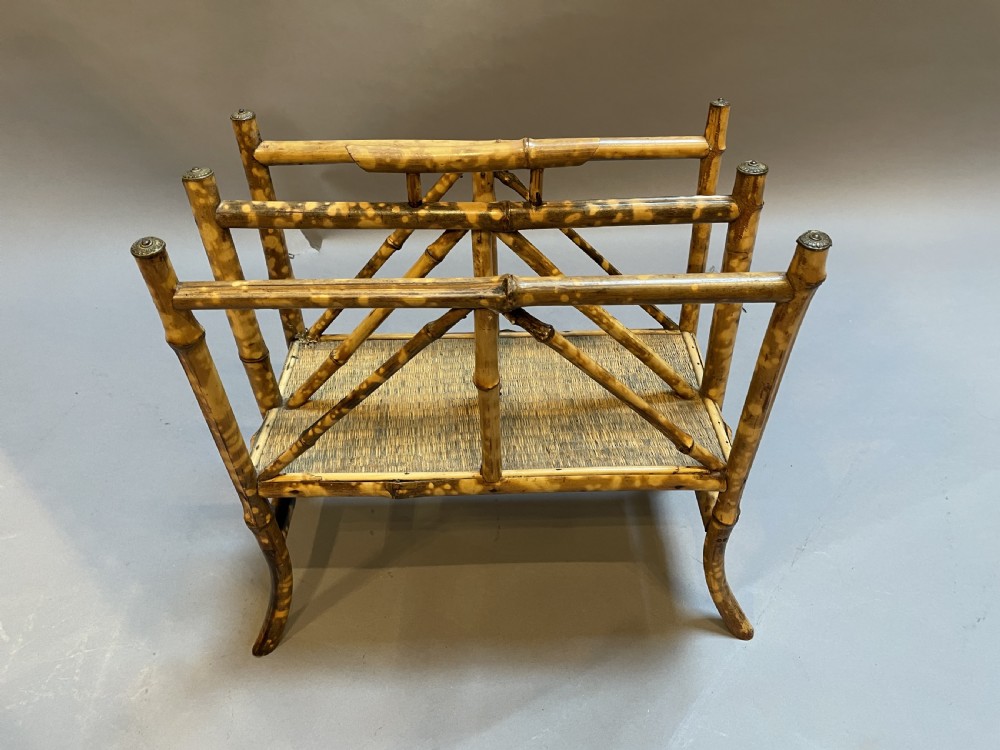 A late 19th-century bamboo canterbury rack featuring diagonal cross-bracing, a woven lower shelf, four partitioned sections, and metal capped finials. View V