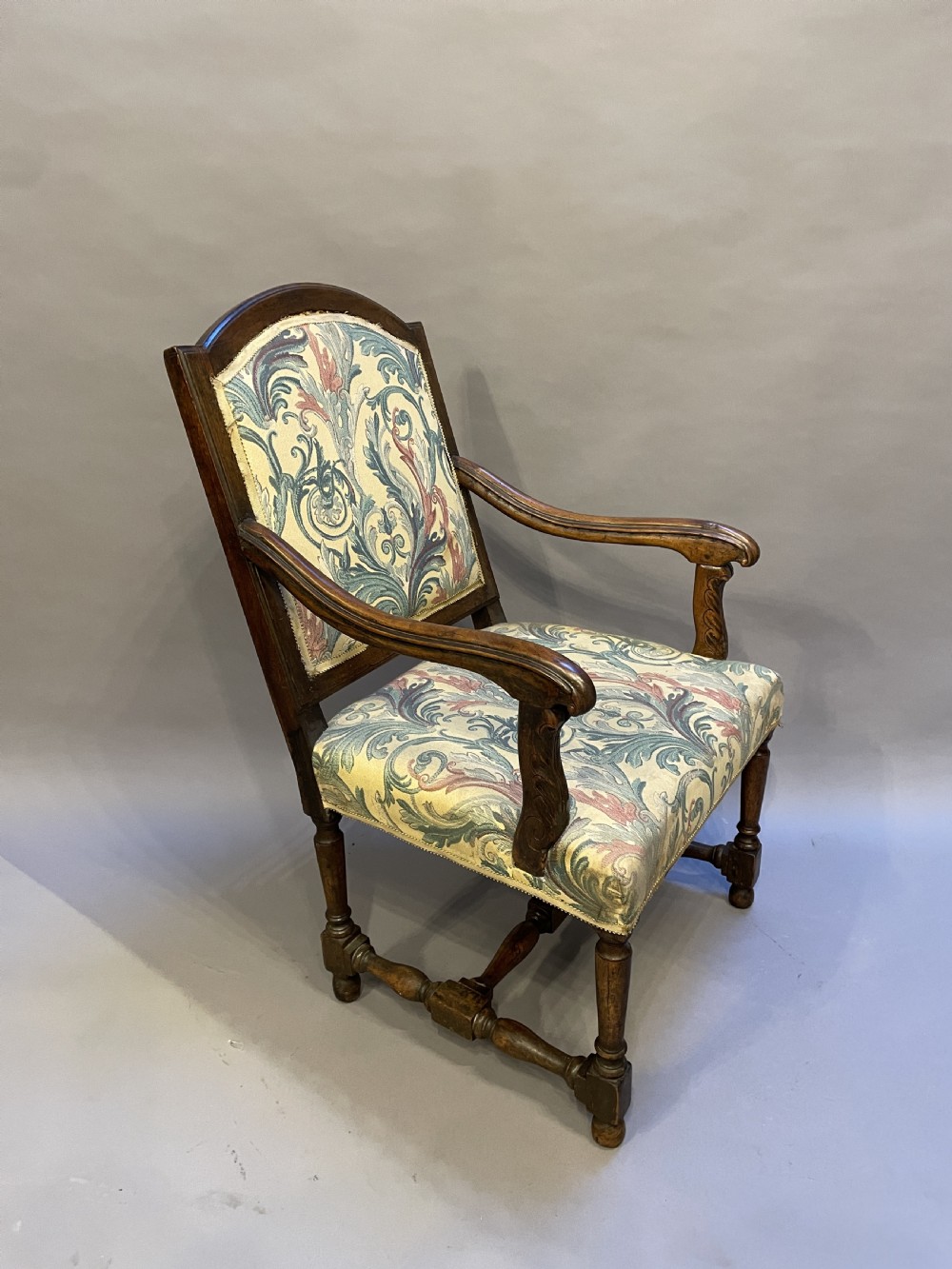 A 19th-century French fauteuil armchair with a carved dark wooden frame, open curved arms, turned stretchers, and leafy tapestry upholstery. View IV