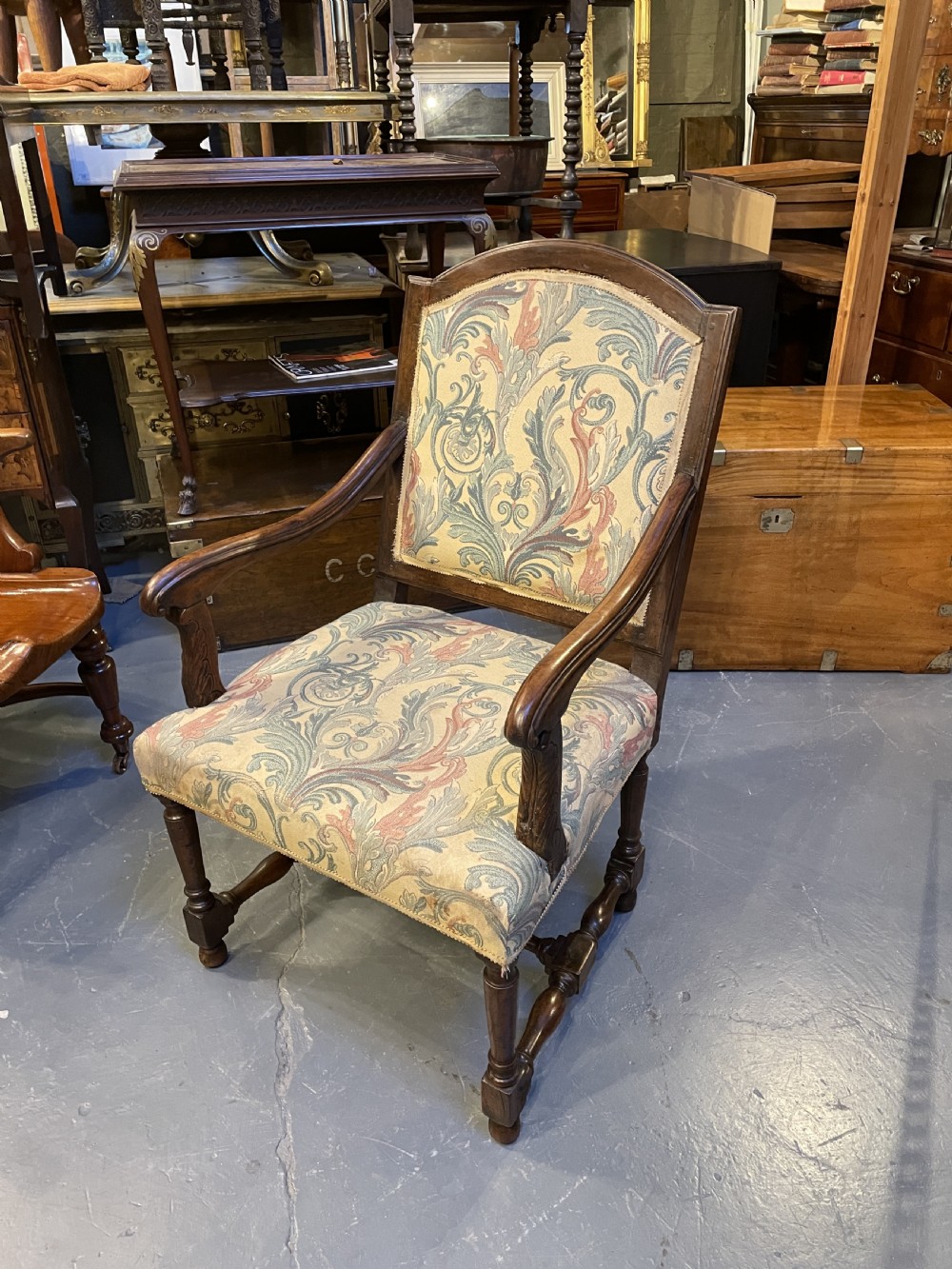 A 19th-century French fauteuil armchair with a carved dark wooden frame, open curved arms, turned stretchers, and leafy tapestry upholstery. View VII