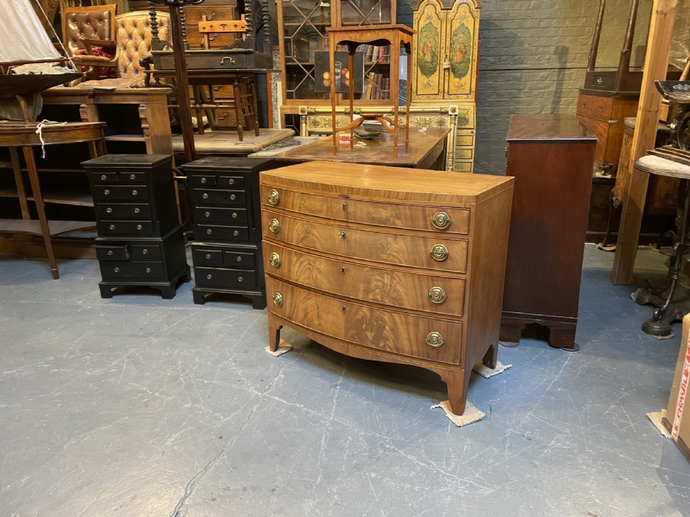 An antique Regency bow-front mahogany chest featuring four graduated drawers with circular brass ring handles on splayed bracket feet. View IV
