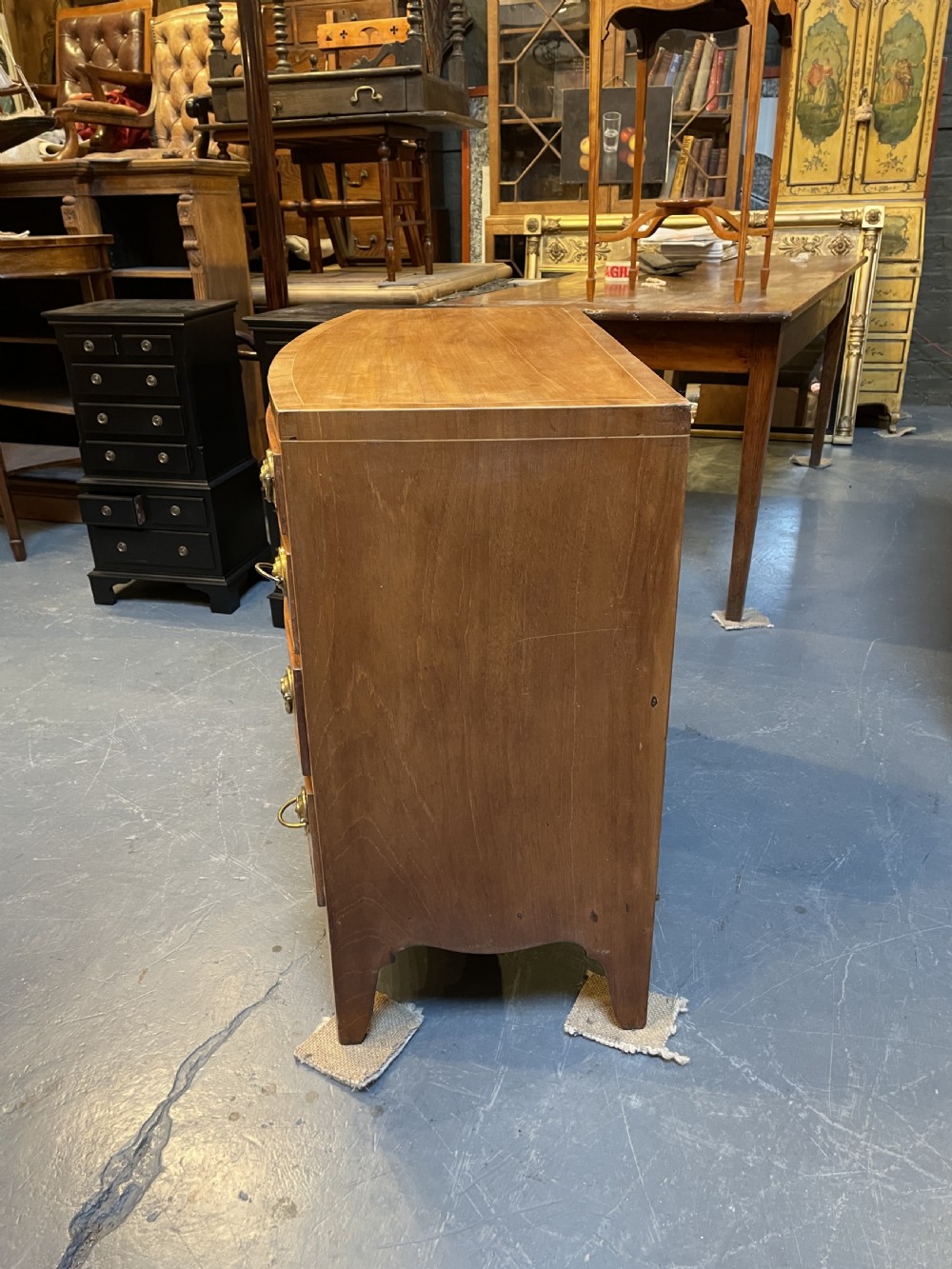 An antique Regency bow-front mahogany chest featuring four graduated drawers with circular brass ring handles on splayed bracket feet. View VI