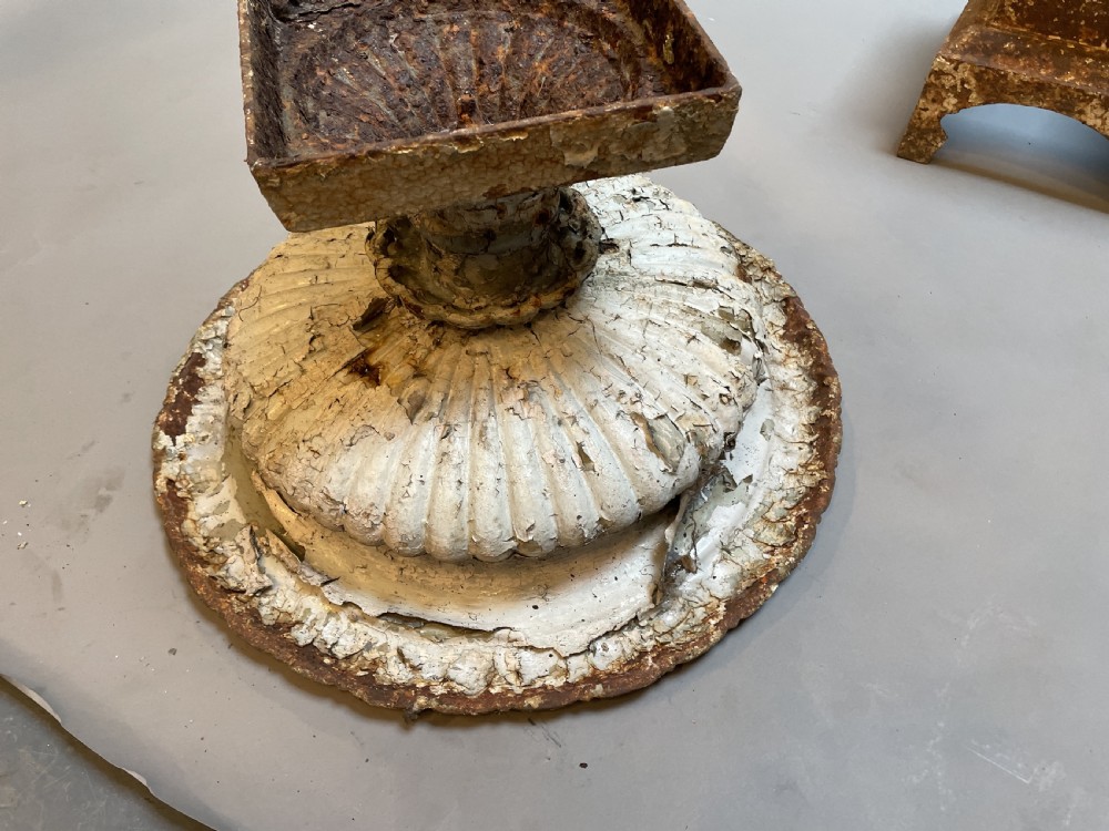 A Victorian cast iron garden urn with a fluted rim and laurel wreath medallion base, displaying a weathered white paint finish over oxidised iron. View VII