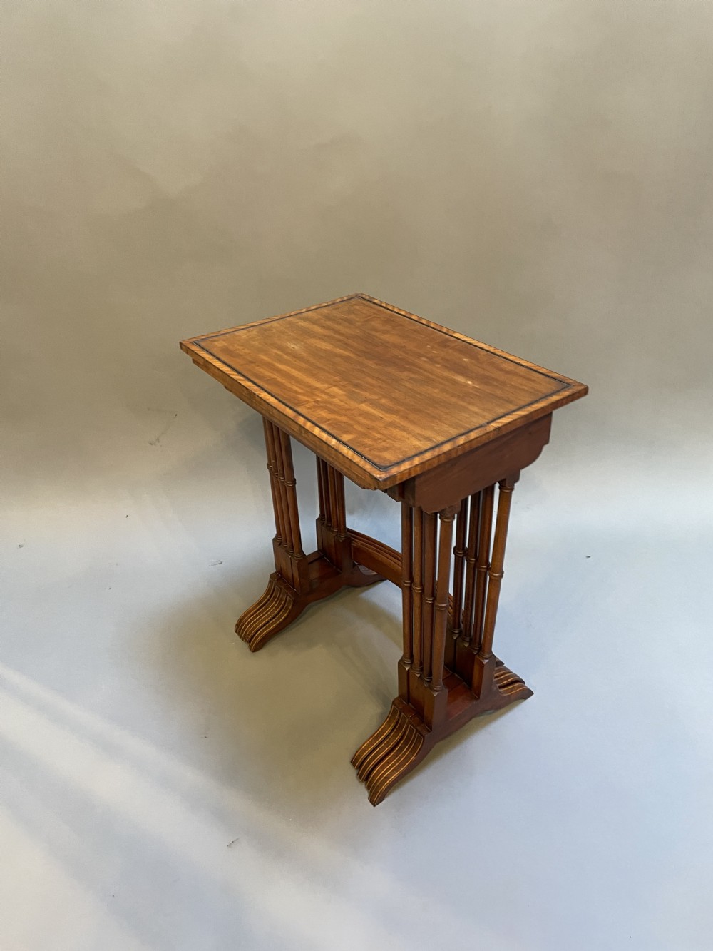 A set of four Edwardian mahogany nesting tables with turned legs, arched stretchers, and inlaid wood borders, arranged in a stepped cascade. View VI