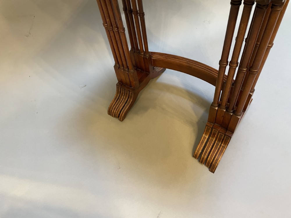 A set of four Edwardian mahogany nesting tables with turned legs, arched stretchers, and inlaid wood borders, arranged in a stepped cascade. View VII