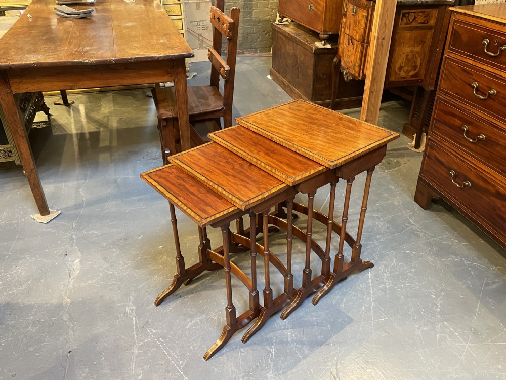 A set of four Edwardian mahogany nesting tables with turned legs, arched stretchers, and inlaid wood borders, arranged in a stepped cascade. View XI