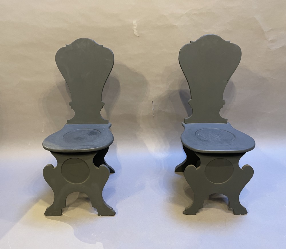 A pair of grey painted wooden Sgabello hall chairs featuring shaped cartouche backs and carved trestle supports. View IV