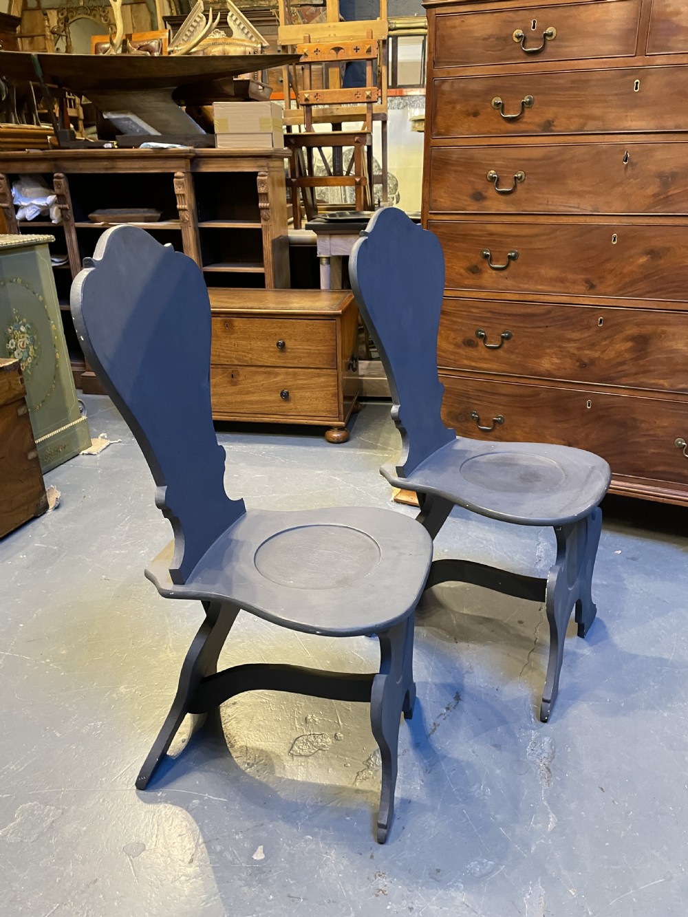 A pair of grey painted wooden Sgabello hall chairs featuring shaped cartouche backs and carved trestle supports. View VI