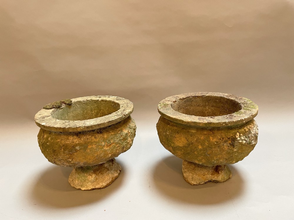 A pair of nineteenth-century carved soft stone garden urns featuring a rounded basin on a short pedestal base with a weathered, textured surface.