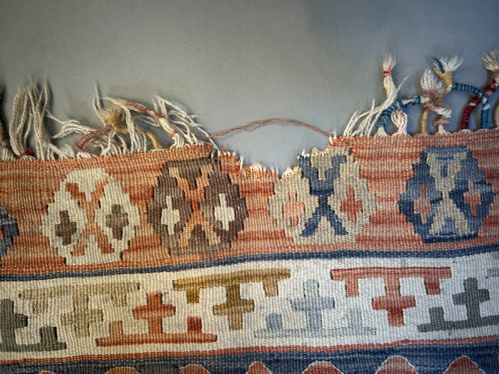 A vintage handwoven Turkish kilim rug featuring geometric tribal patterns in terracotta, indigo blue, and cream with fringed edges. View IV