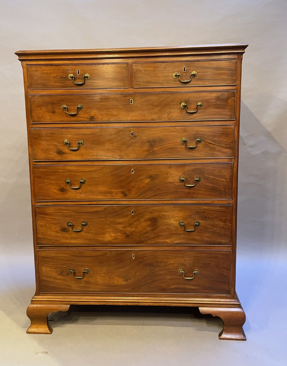 A George III mahogany tall chest of drawers featuring two short over five long graduated drawers with brass swan-neck handles and bracket feet. View II