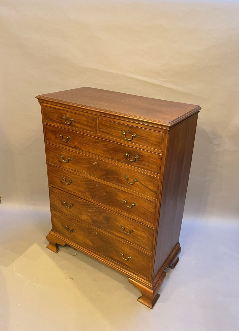A George III mahogany tall chest of drawers featuring two short over five long graduated drawers with brass swan-neck handles and bracket feet. View VI