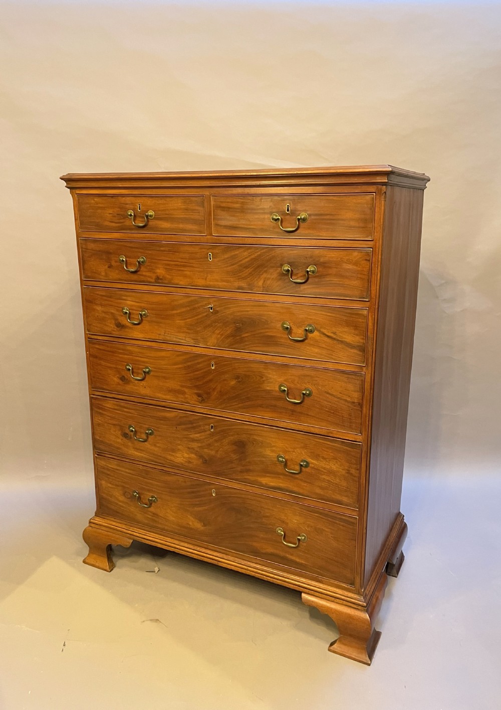 A George III mahogany tall chest of drawers featuring two short over five long graduated drawers with brass swan-neck handles and bracket feet. View XXVII