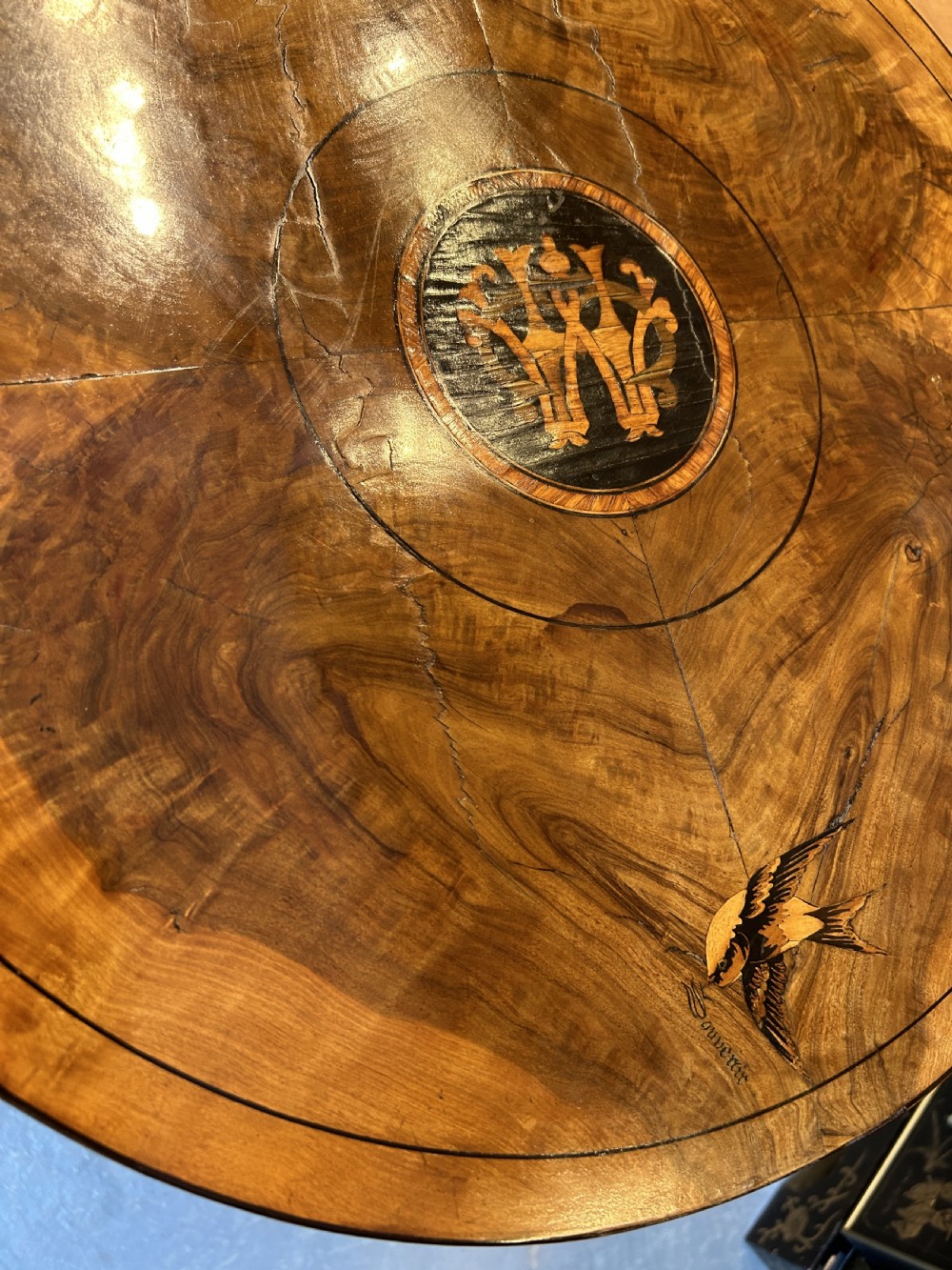 A 19th-century Italian circular occasional table made of warm brown burr walnut with a central marquetry motif, three bobbin-turned legs, and a lower tier shelf. View III