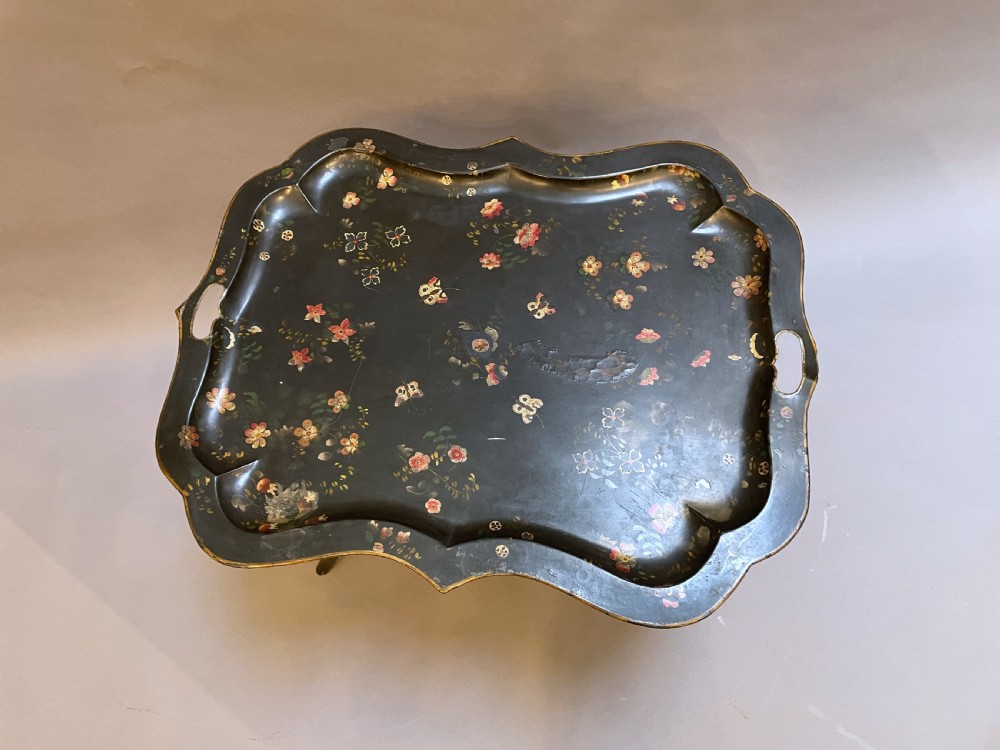A Victorian black painted toleware tray table with hand-painted floral motifs, a scalloped edge, and faux bamboo legs. View II