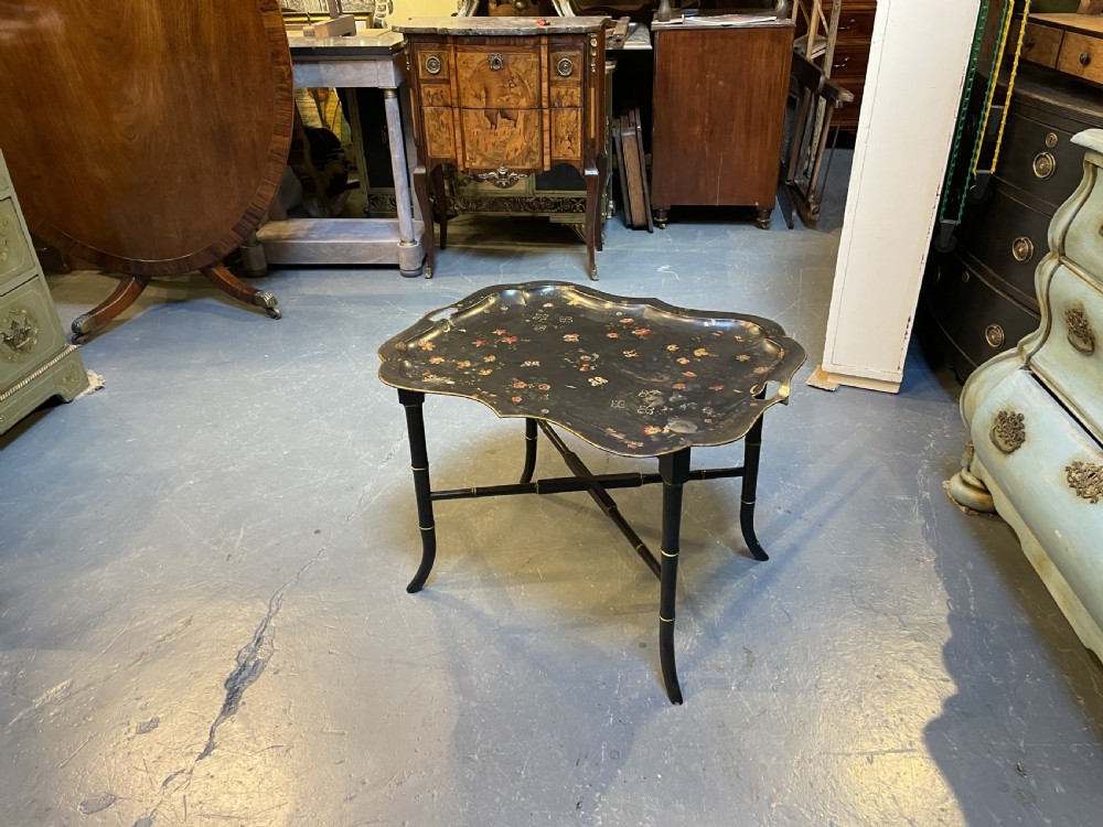 A Victorian black painted toleware tray table with hand-painted floral motifs, a scalloped edge, and faux bamboo legs. View V